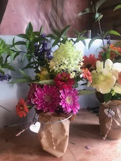 A mixed bouquet of zinnias and hydrangea wrapped in brown paper